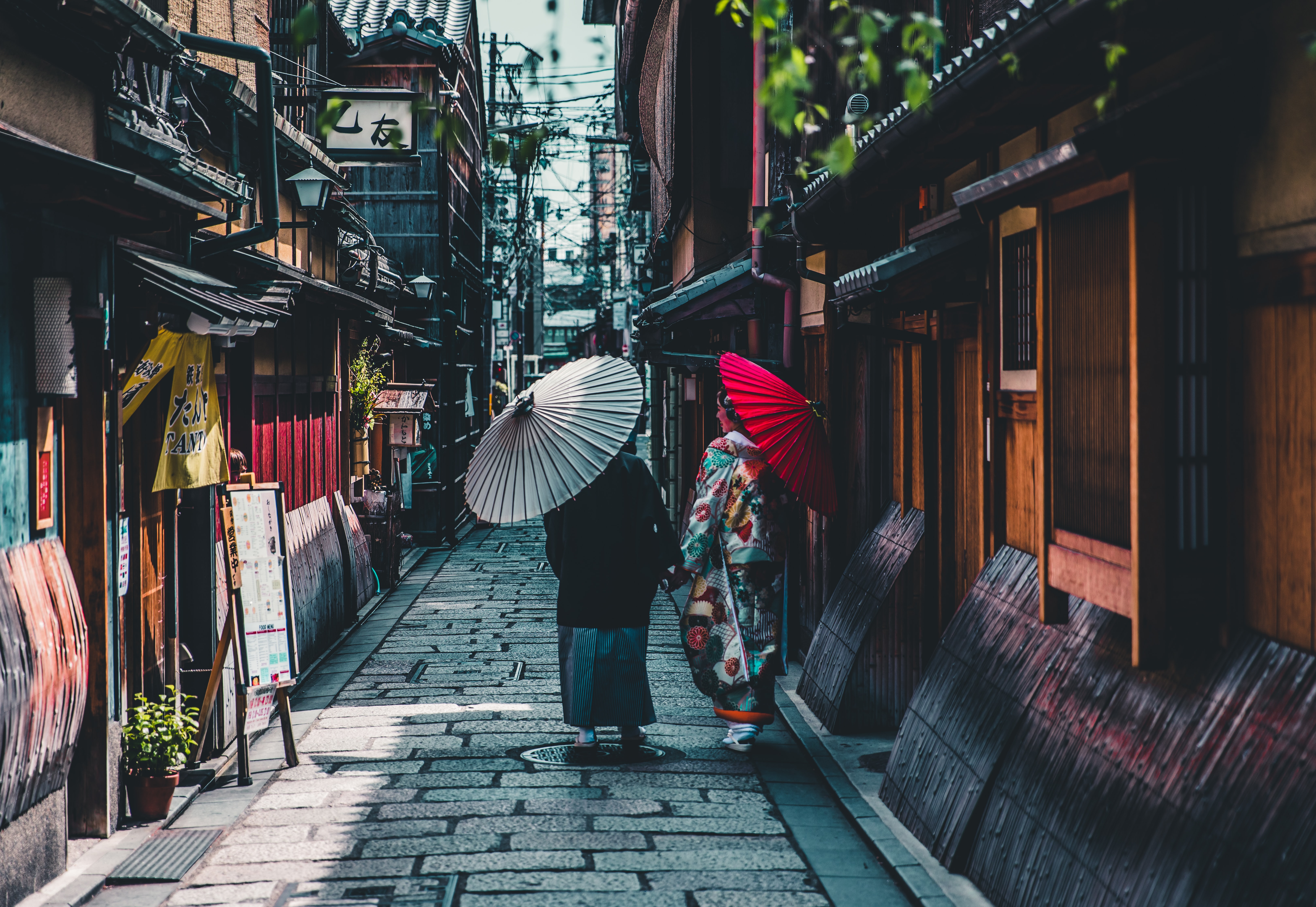Couple walking on street while holding umbrella in Kyoto
