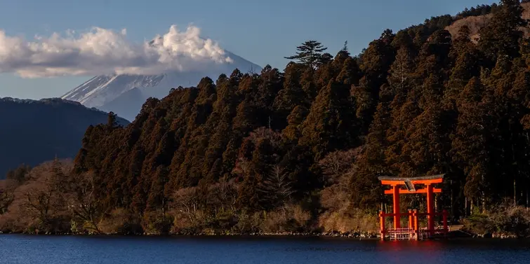 Torii gate on a lake edge with Mt Fuji in the background.